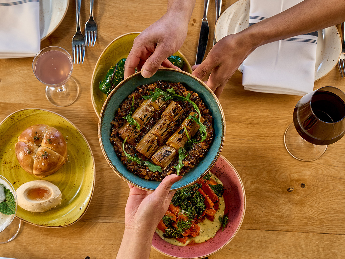 A leek small plate is passed between hands at a table